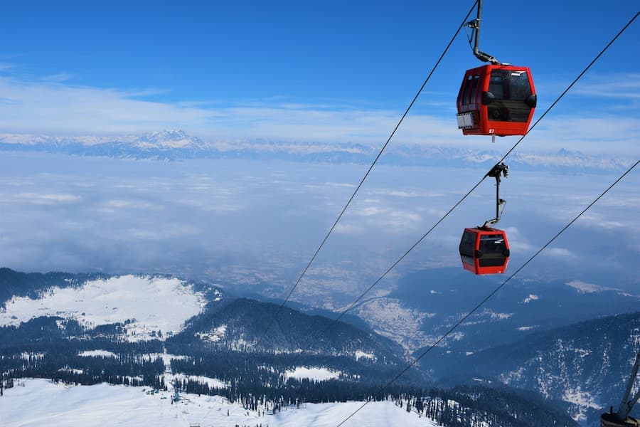 Cable car ascending over pine forests toward the Himalayas