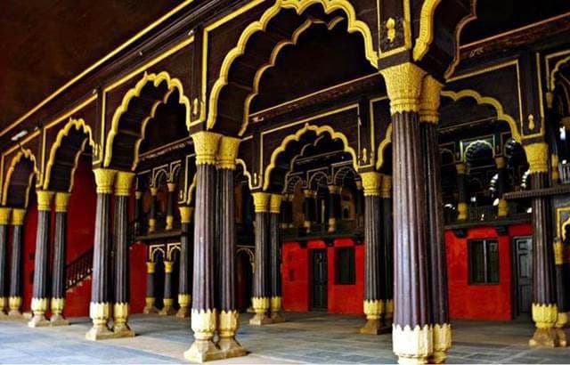 Muslim travelers exploring Tipu Sultan's Summer Palace's teakwood carvings in Bangalore