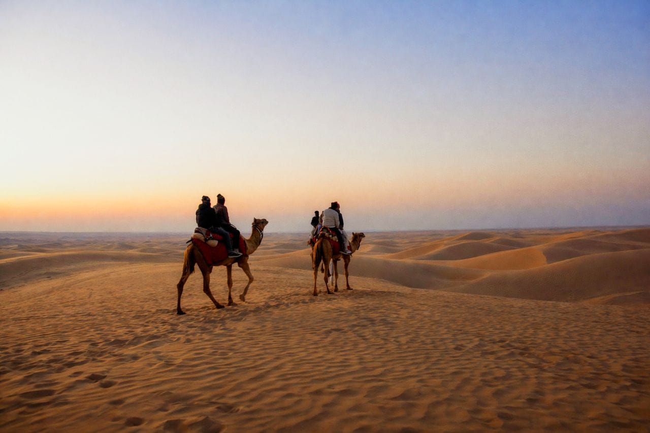 Muslim family enjoying a camel safari across the Thar Desert dunes near Jaisalmer