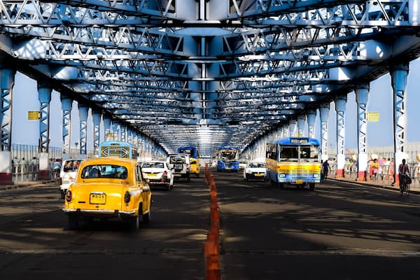 Kolkata's iconic yellow taxi crossing Howrah Bridge, a beloved symbol of the city's cultural identity